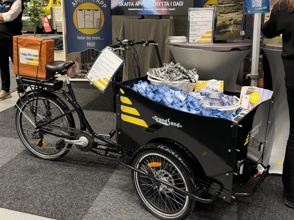 Lådcykel fylld med giveaways i en mässmonter.